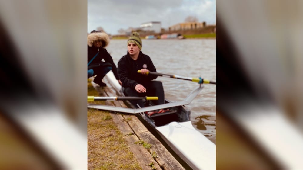 Student sat in boat holding oars on a business trip at stratford college