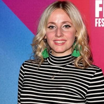 Sinead standing wearing black and white top and orange skirt