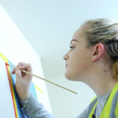 student painting on wall at Stratford-Upon-Avon College