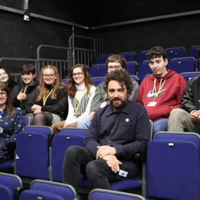 Greg McLeod sitting with students and tutor at stratford-upon-avon college