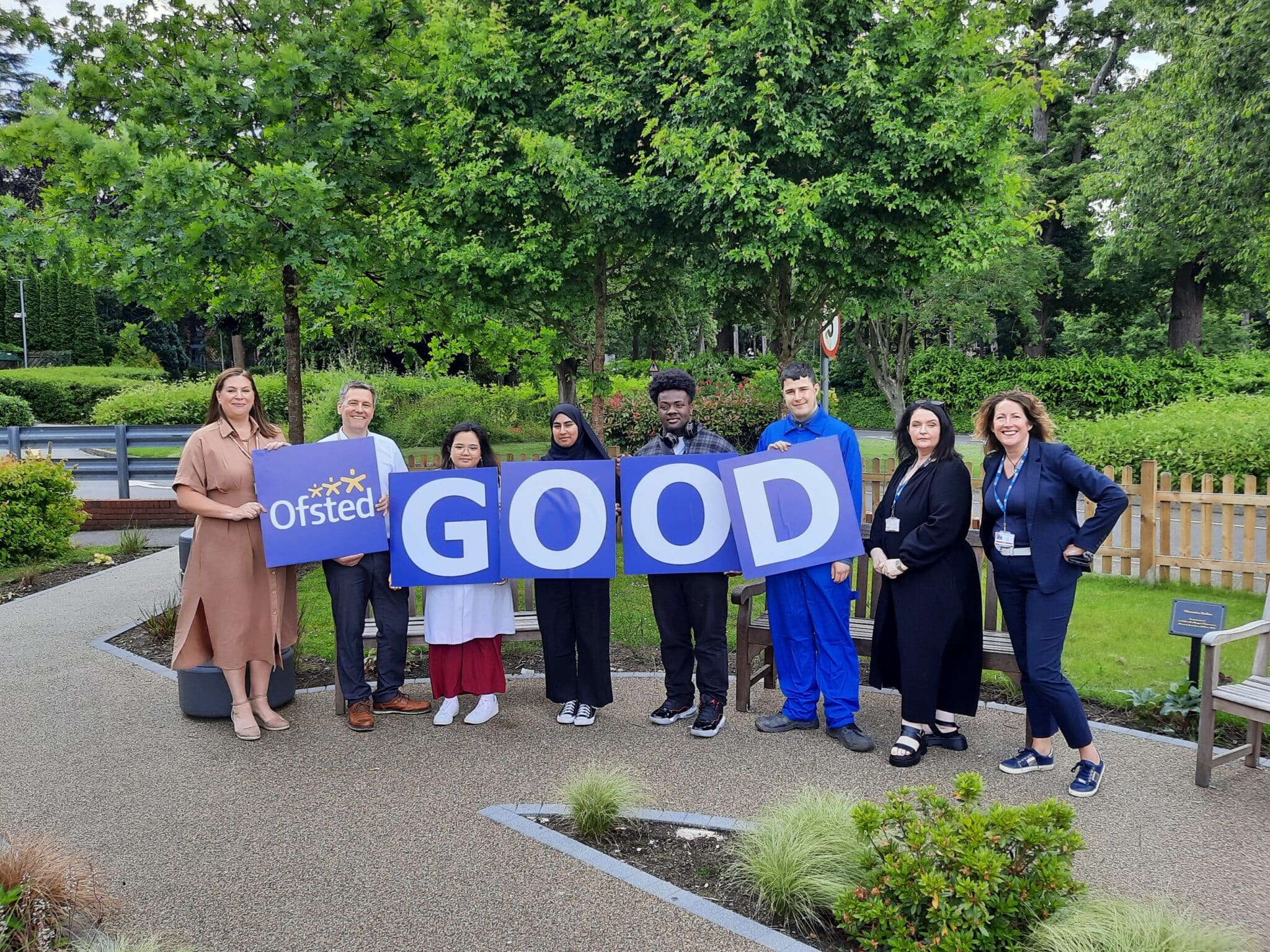 students and staff with signs reading GOOD