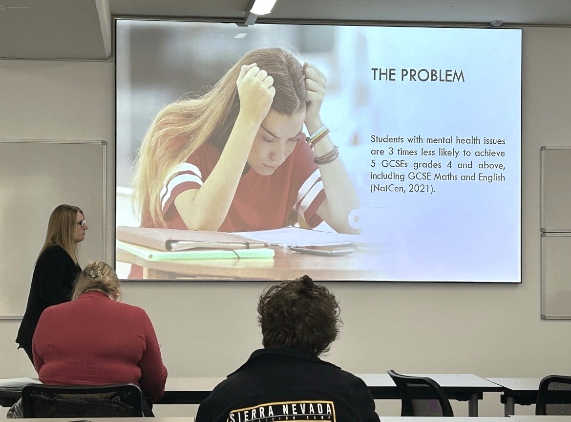 Lecturer stood at the front of a room giving a presentation at Stratford College