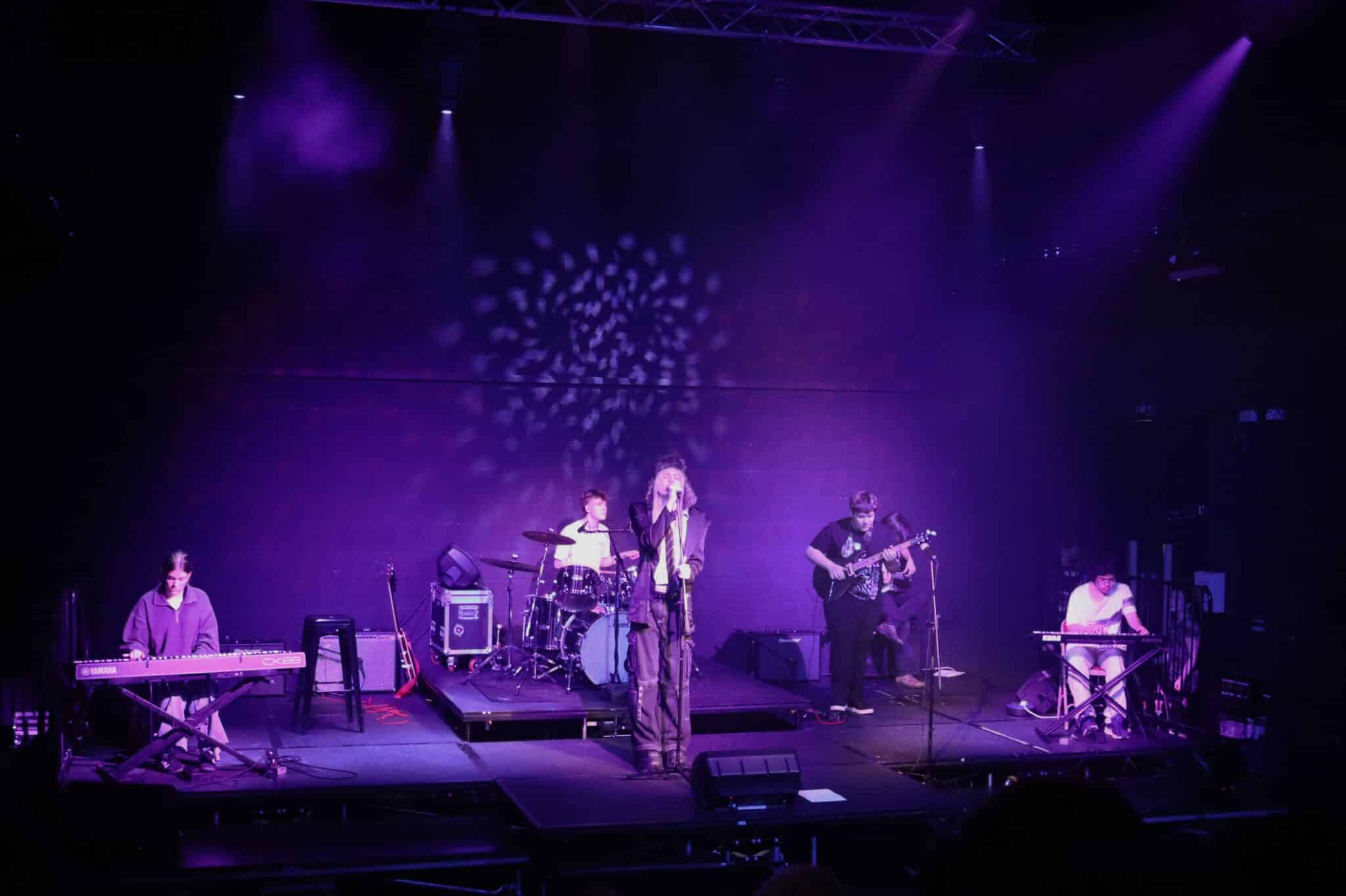 Stratford College Students perform a concert on a stage under purple lights