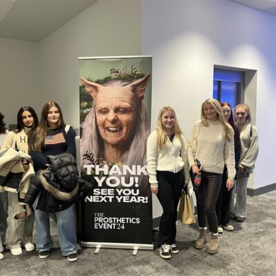 Make Up Students stood at a sign for an event.