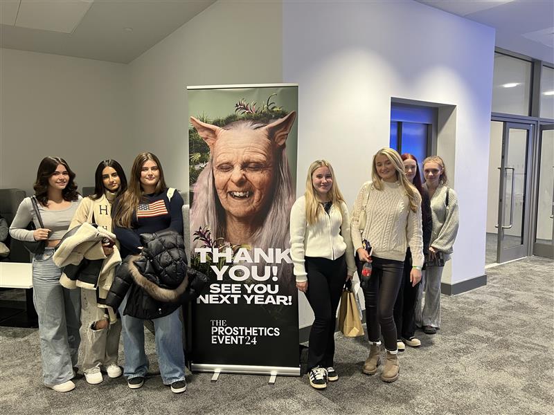 Make Up Students stood at a sign for an event.