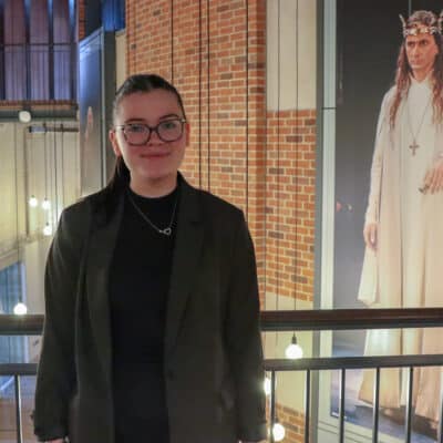 A girl with glasses standing in front of a balcony