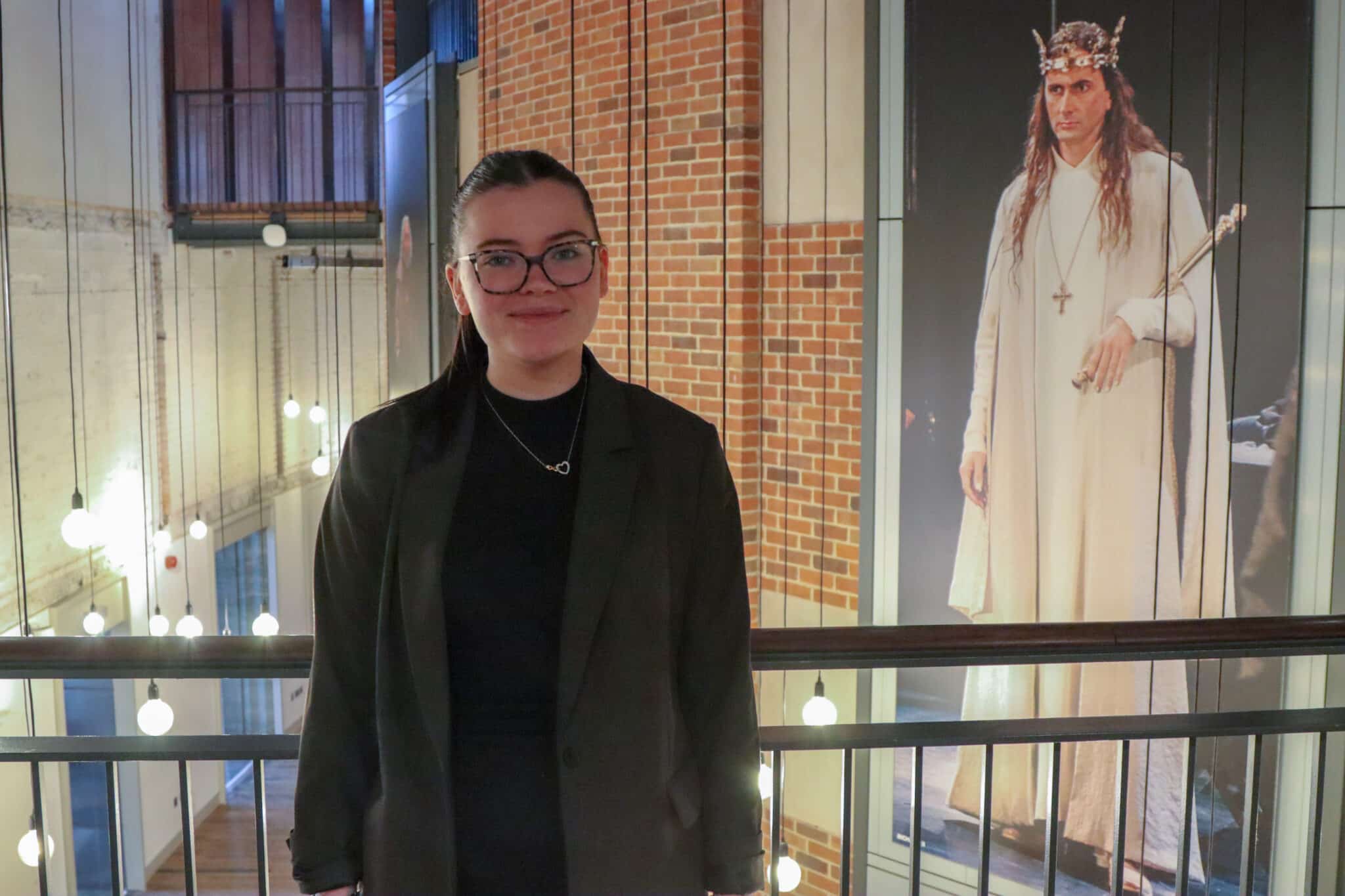 A girl with glasses standing in front of a balcony