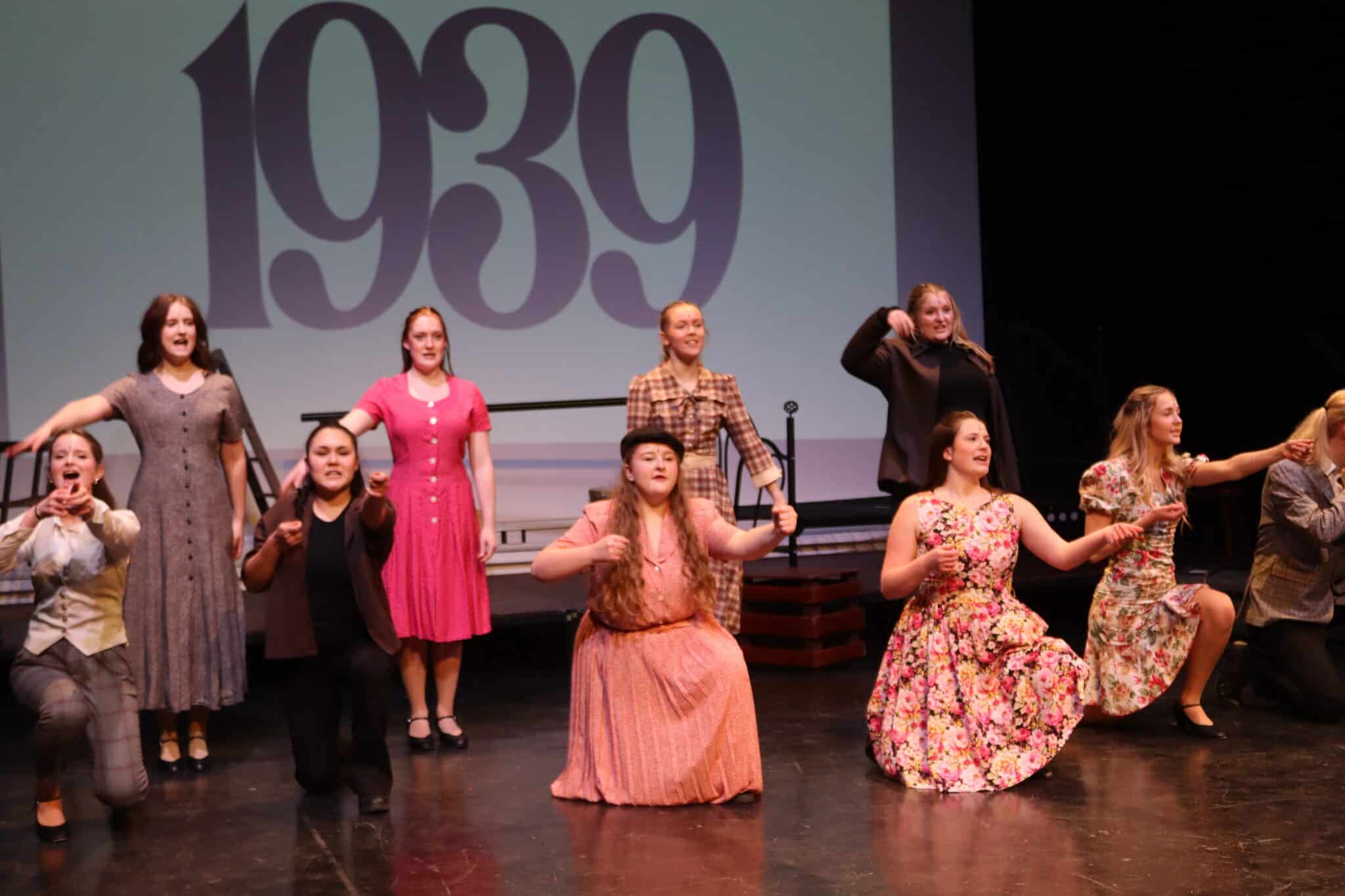 People kneeling on stage in floral dresses