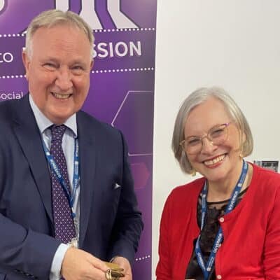 Two people smiling as a lady hands over a set of keys