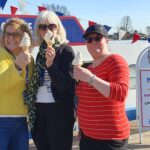 women stood in front of canal boat holding ice cream.