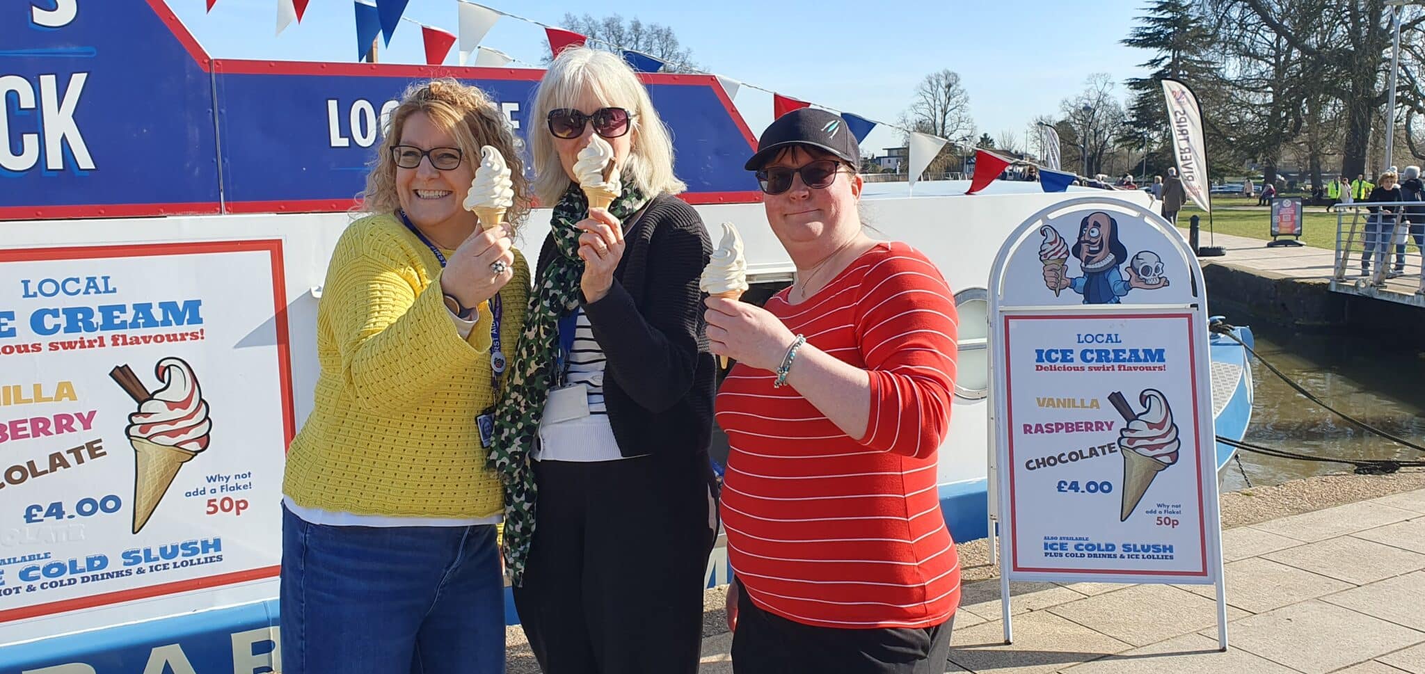 women stood in front of canal boat holding ice cream.