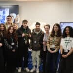 A group of students and their tutors smiling at the camera holding a trophy.