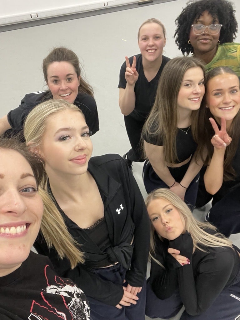 Students and teacher smiling in a selfie.